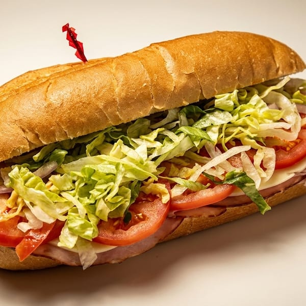 A large deli sub sandwich filled with ham, cheese, tomatoes, onions, and shredded lettuce.